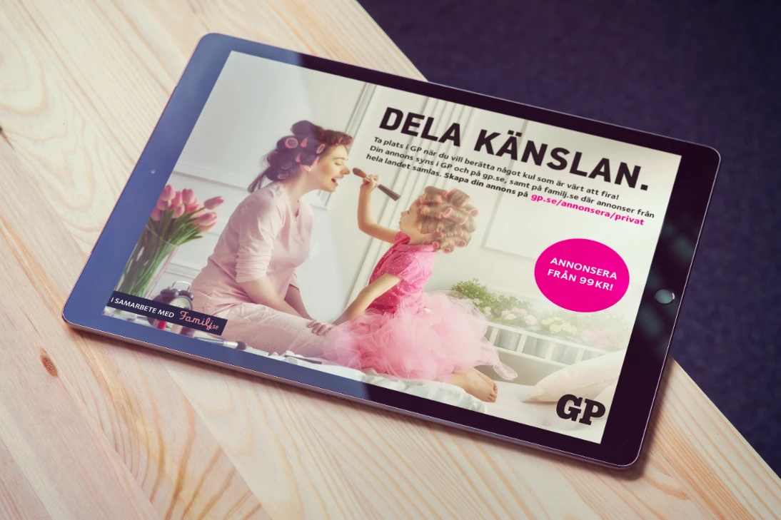 En bild på en ipad på ett bord mot svart bakgrund med en annons för Familjesidan. Annonsen har rosa detaljer.